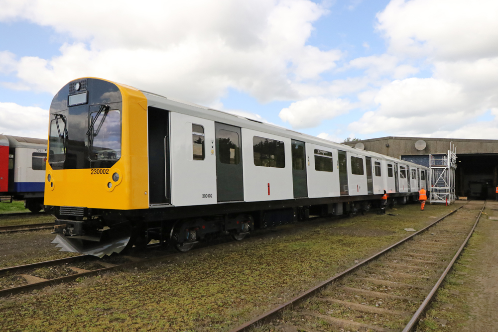 White passenger train of multiple-unit cars with yellow noise and black doors