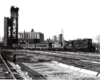 Conrail passenger trains: Two high hood locomotives lead a train through bridge piers.