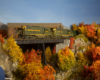 A pair of green-and-yellow Geeps step out onto a trestle amid brilliant fall foliage.