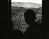 Silhouette of a man looking out the door of a passenger car.