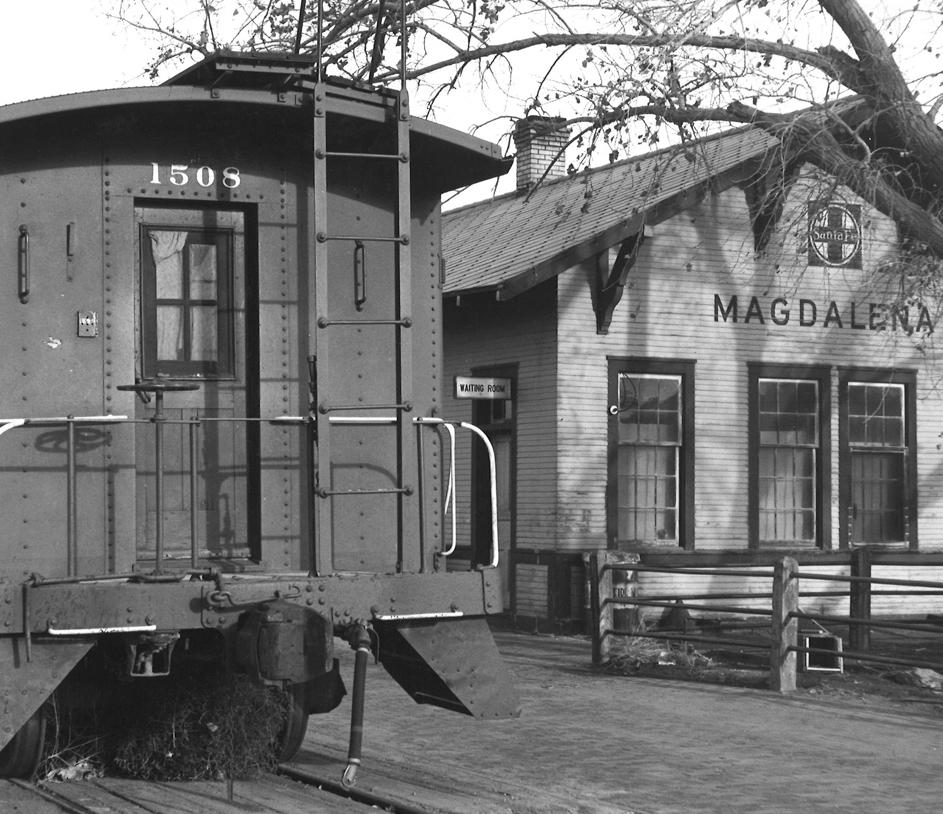 Caboose next to wooden train station.
