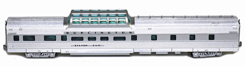 Side view of lightweight fluted-side dome-buffet car painted silver with black graphics and green-tinted dome glazing.
