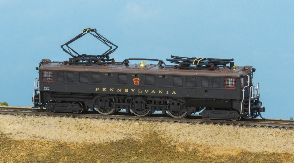 Photo of N scale electric locomotive with rear pantograph raised on scenicked backdrop.