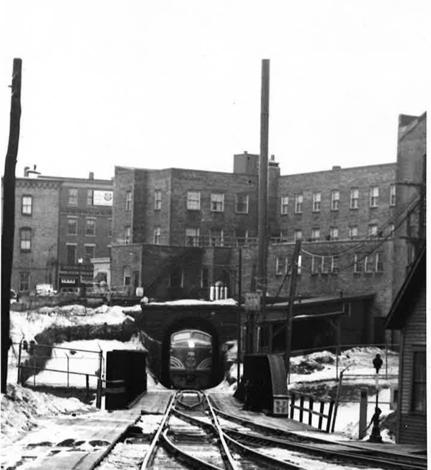 Bellows Falls tunnel under a town prototype: Black and white image of a freight train exiting tunnel underneath a town.