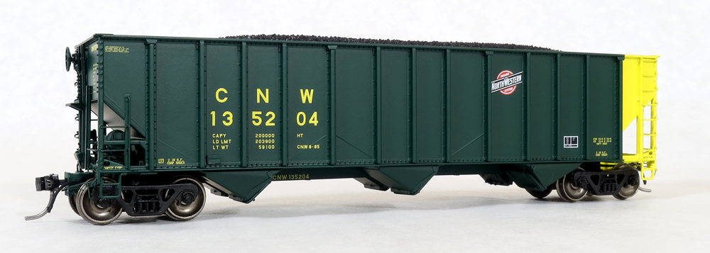 Photo of HO scale three-bay hopper painted green with yellow, red, white, and black graphics and coal load on white background.