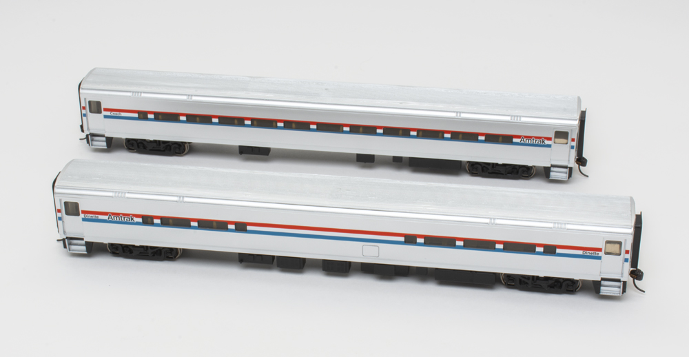 Photo of Amtrak HO scale Horizon coach and dinette in phase 3 paint scheme on white background.