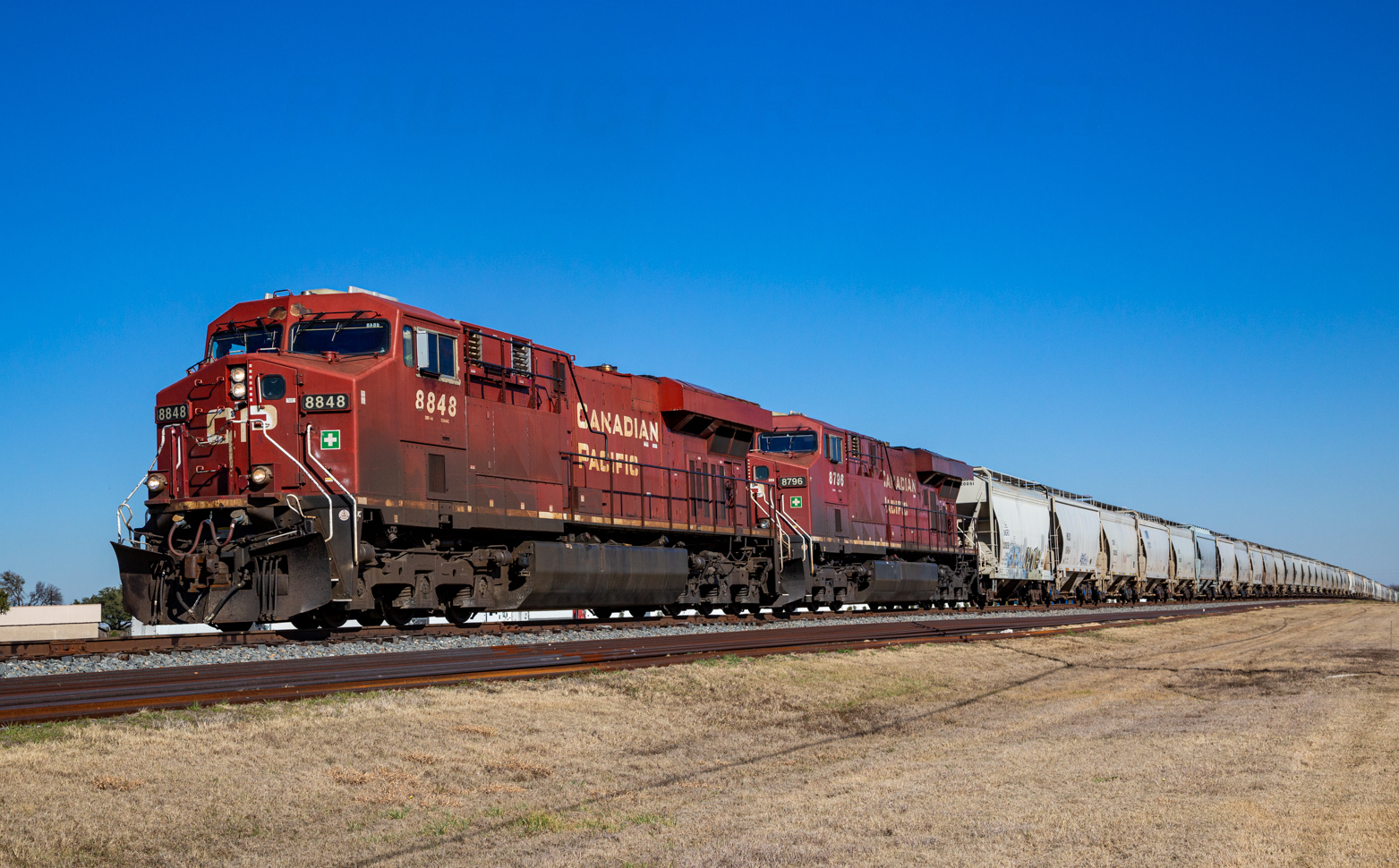 Train with red locomotives and covered hopper cars