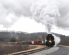 Big plume above black steam engine coming around a bend