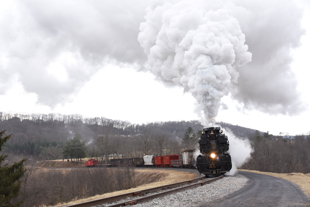 Big plume above the black steam engine coming around a bend