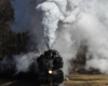 Smoke fills the frame with nose of black steam engine