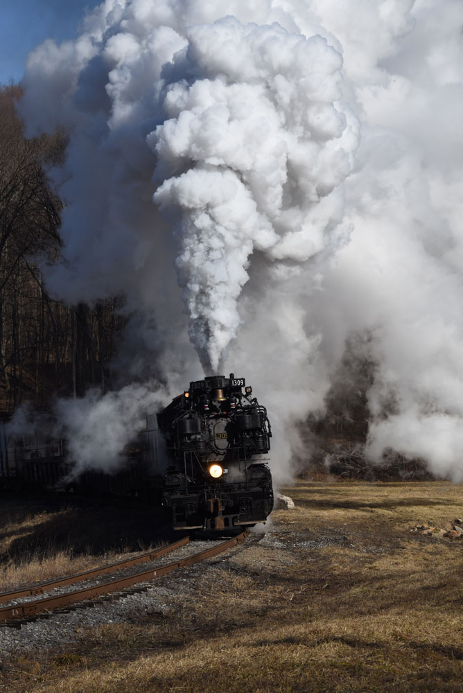 Smoke fills the frame with nose of black steam engine