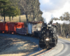Black steam engine with photo freight comes around a horseshoe curve