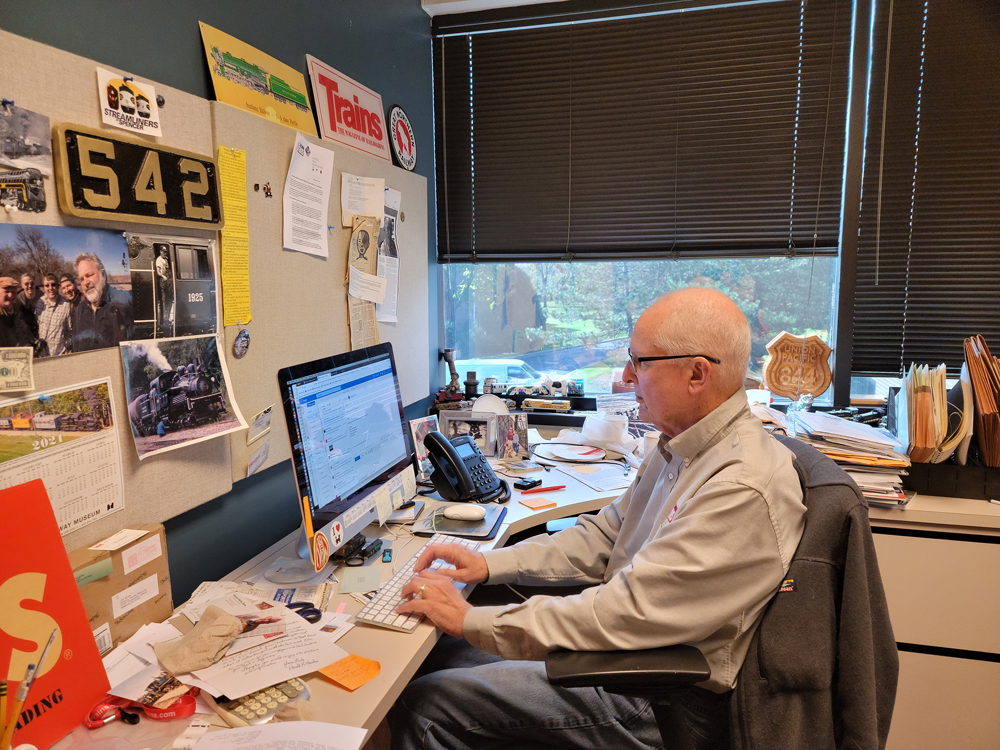 Man at work at computer in office full of rail memorabilia