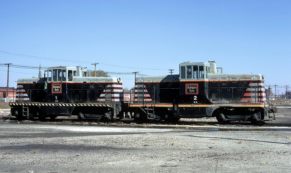 Black and silver center cab locomotives in a rail yard.
