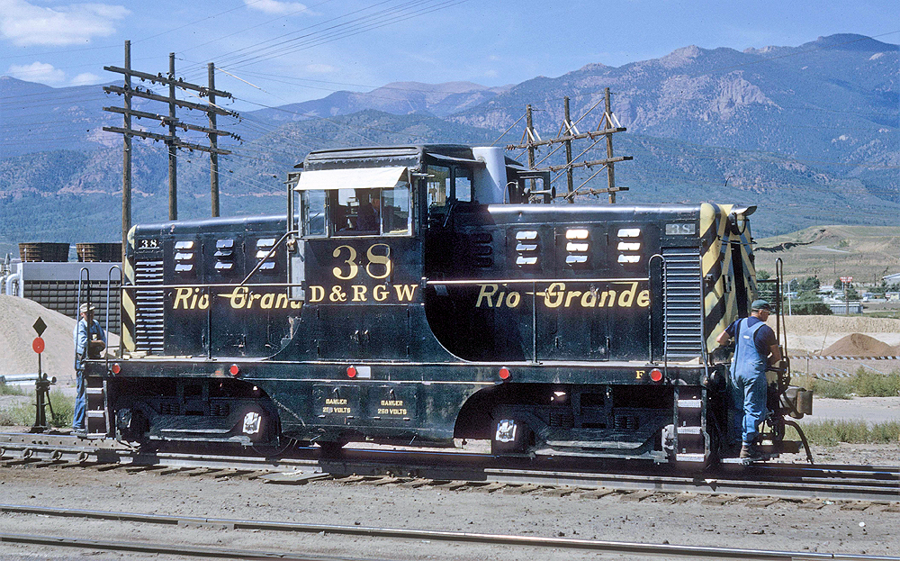 Black and yellow-accented center cab locomotive in a rail yard.