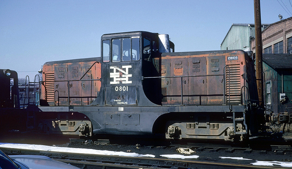A grimy black and orange center cab locomotive.