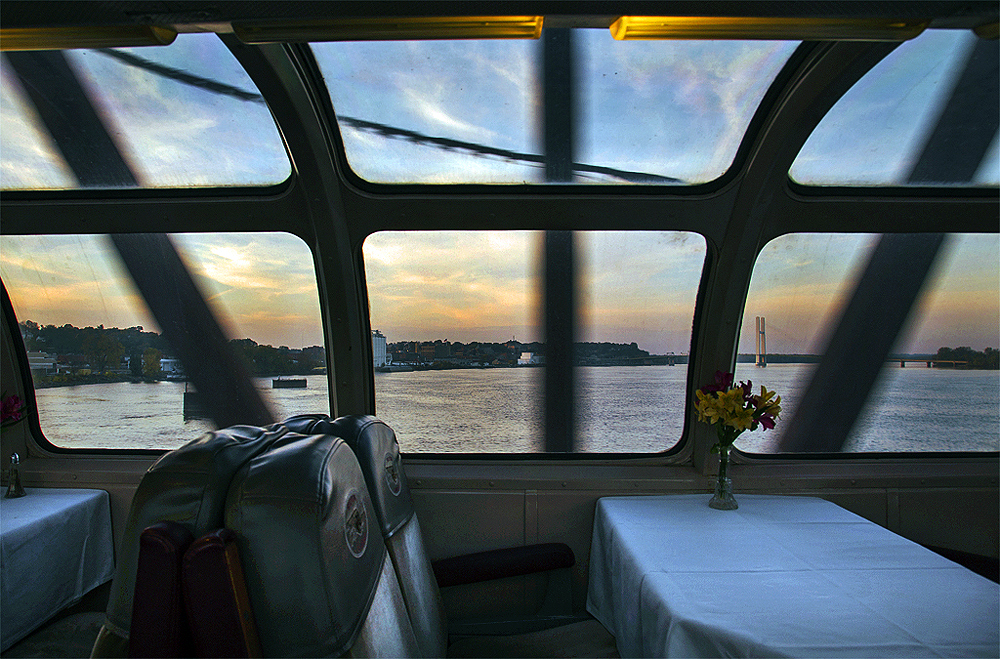 View of river at sunset through a passenger car window.