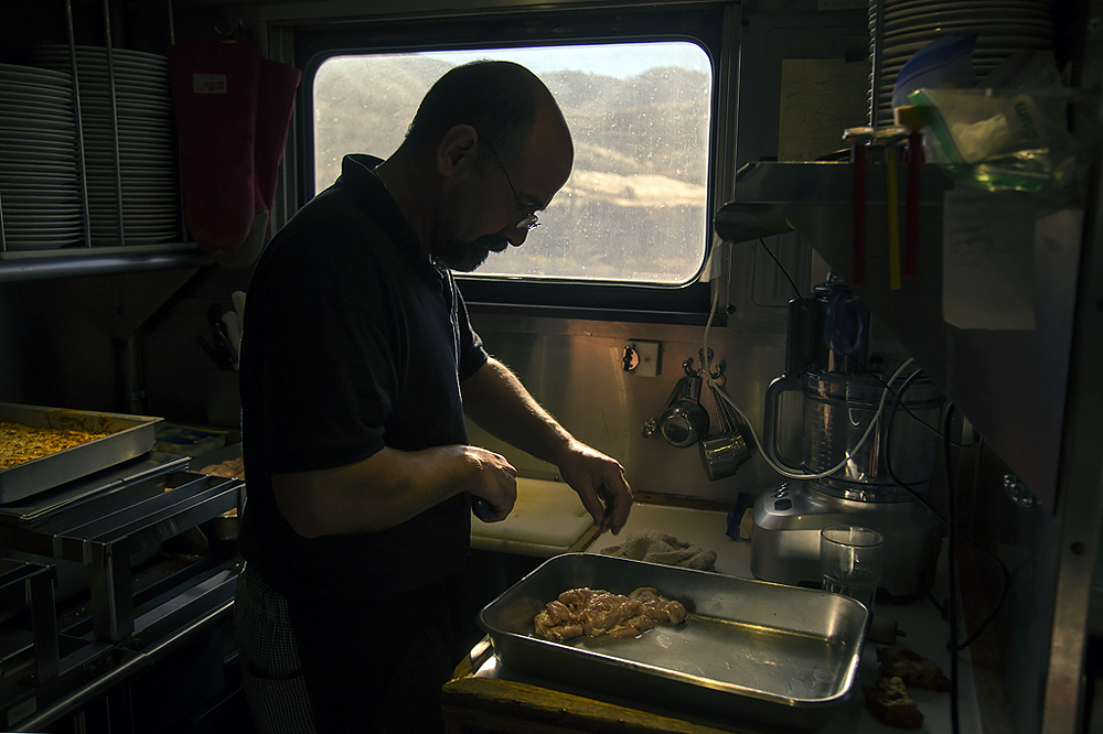 Silhouette of a man preparing food in a passenger car kitchen.