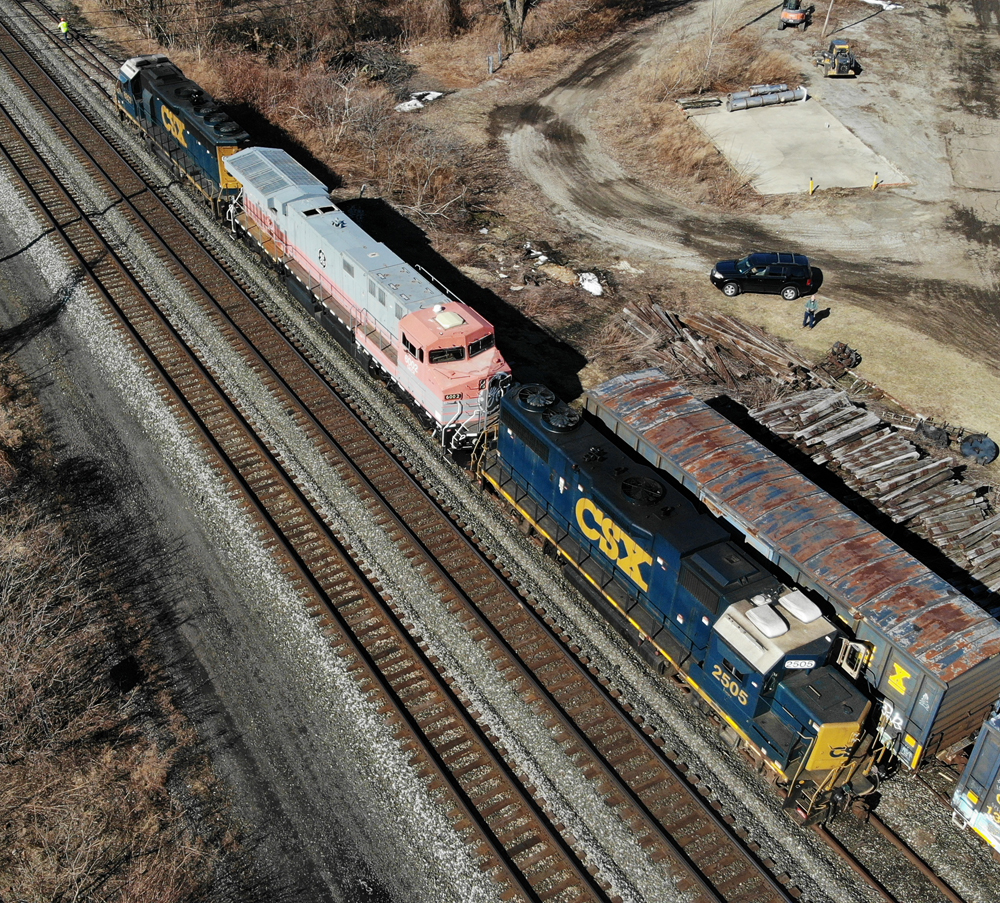 Pink and gray locomotive between two blue and yellow locomotives