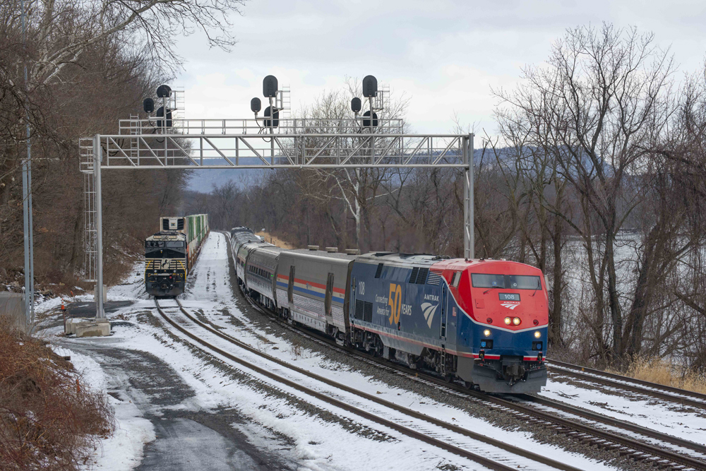 Passenger train with blue and red locomotive passes freight train