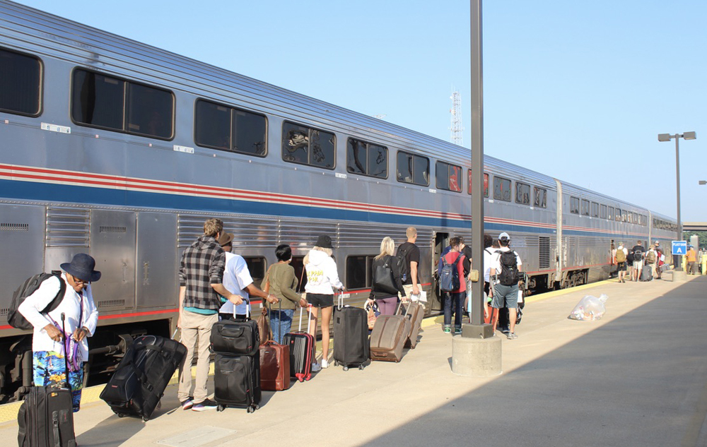 People with luggage on platform next to train