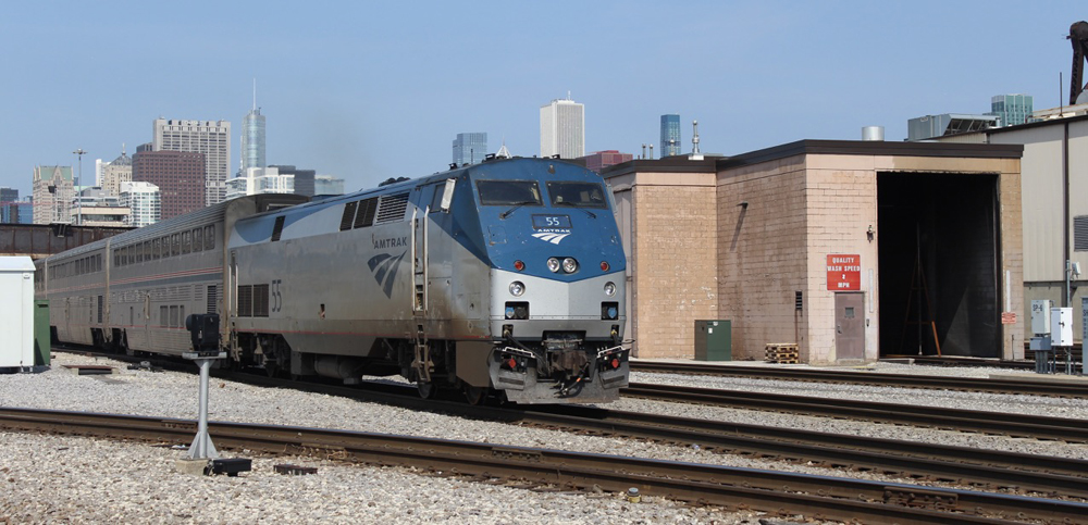 Train passes brick structure on an adjacent track
