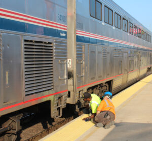 Two workmen on ground next to passenger car