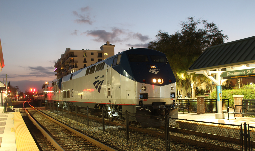 Passenger train stops at station at dusk