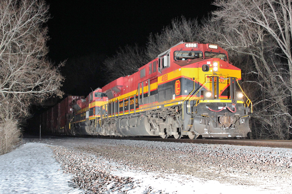 Train with red, yellow, and black diesels operating at night