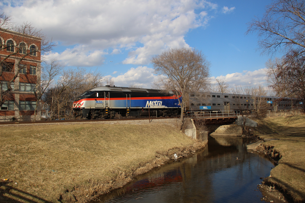 Commuter train crossing bridge over stream