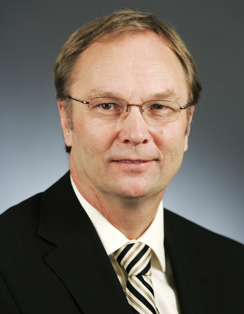 Man with glasses wearing coat and tie
