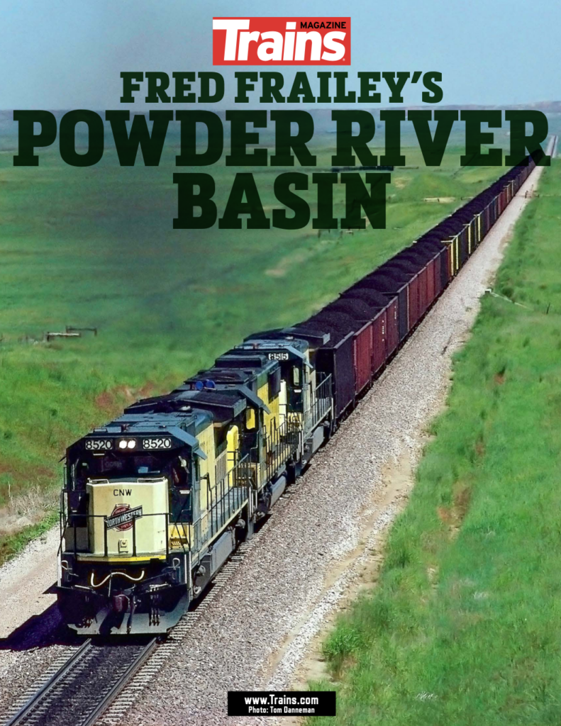 Green and yellow locomotives lead a coal train through green grasslands. Title: Fred Frailey's Powder River Basin.