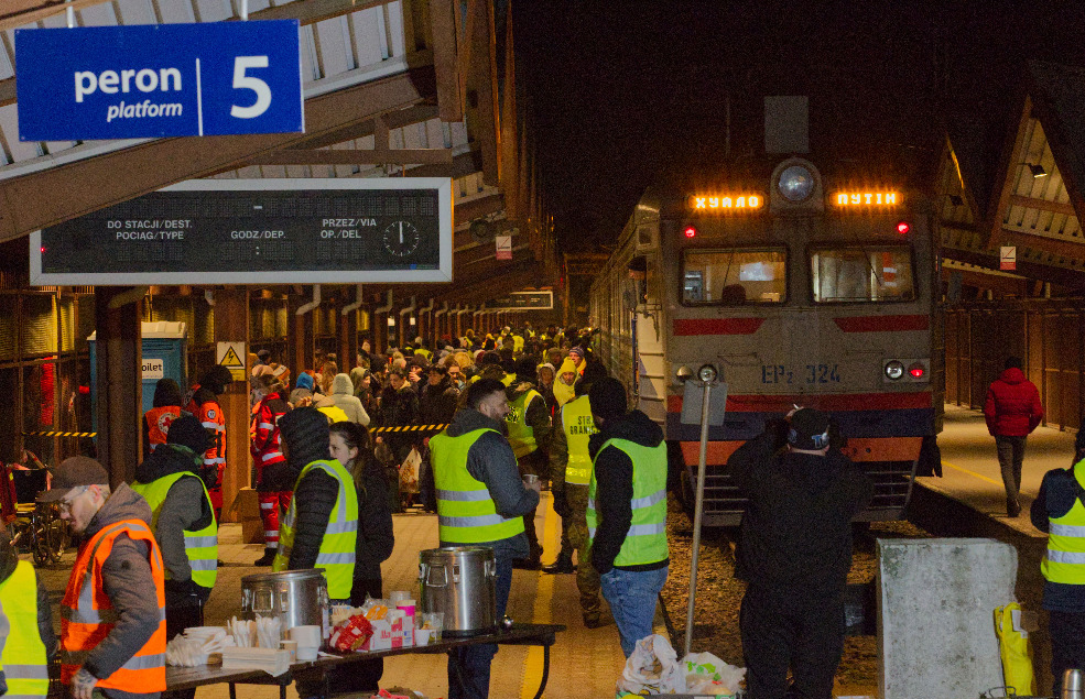 Passengers and aid workers on station platform with train in background