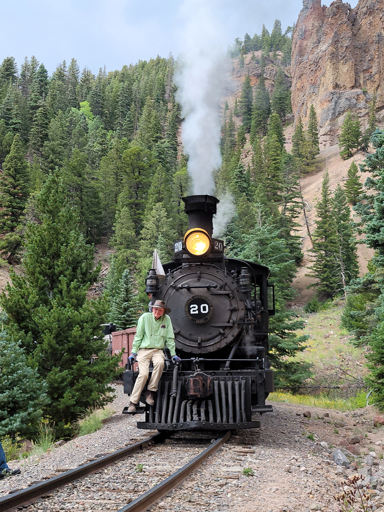 Man riding on pilot of steam locomotive