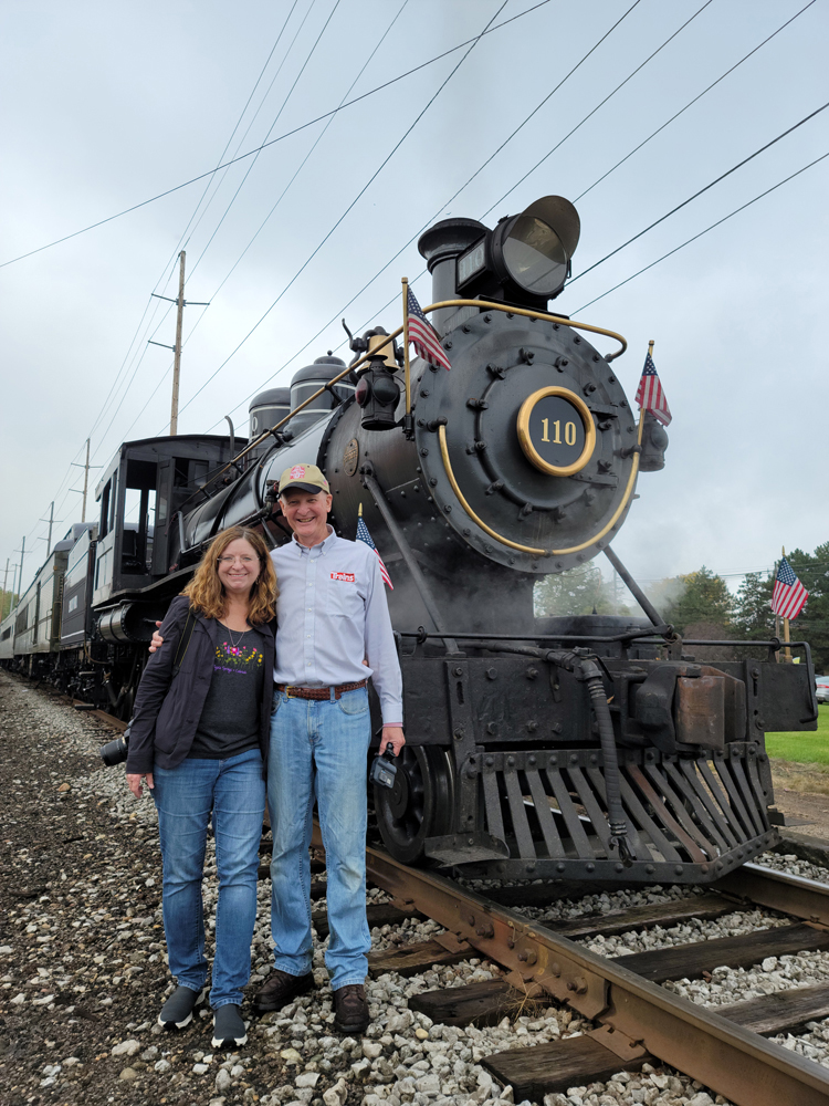 Woman and man standing in front of steam locomotive