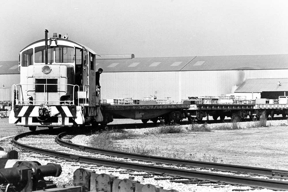 EMD Model 40 centercab diesel locomotive with empty flatcars on curve