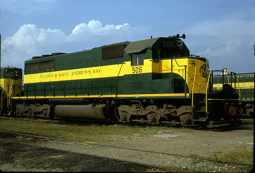 Green and yellow diesel locomotive in a rail yard.