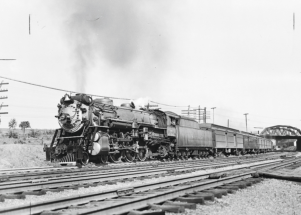 Black and white image of a steam locomotive pulling a passenger train.