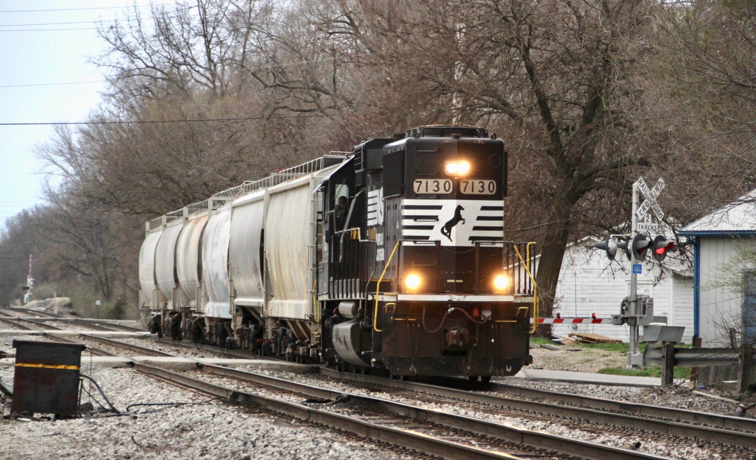 A six-car local freight train led by a black and white diesel engine. first-mile, final-mile markets