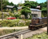 A boy on a bicycle riding down a dirt road waves to the engineer of a passing train