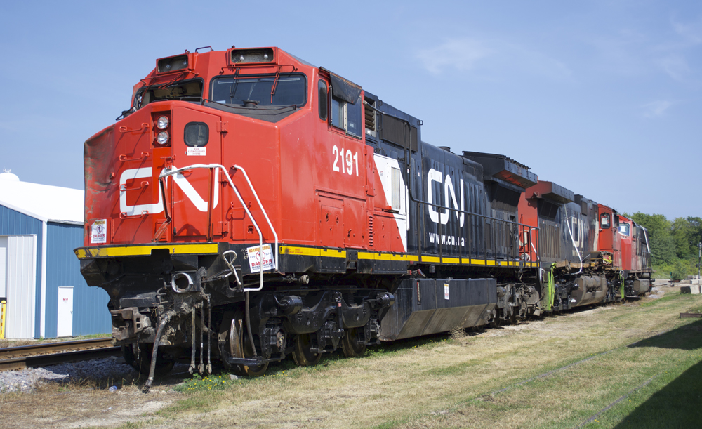 Transporting a damaged locomotive: The wreck-damaged locomotives painted red, white, and black on a siding.