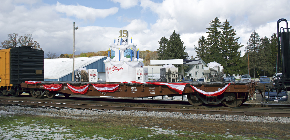 Photo of flatcar painted brown with red and white bunting.
