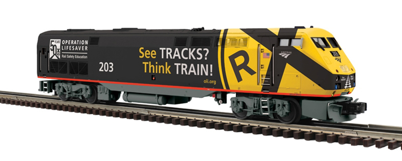 Photo of O gauge General Electric P42 diesel locomotive painted black with large yellow railroad crossing warning sign on nose and black and white graphics on white background.