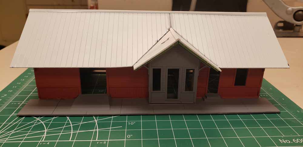 The building now has a different looking entrance and a roof made from white styrene metal roofing.