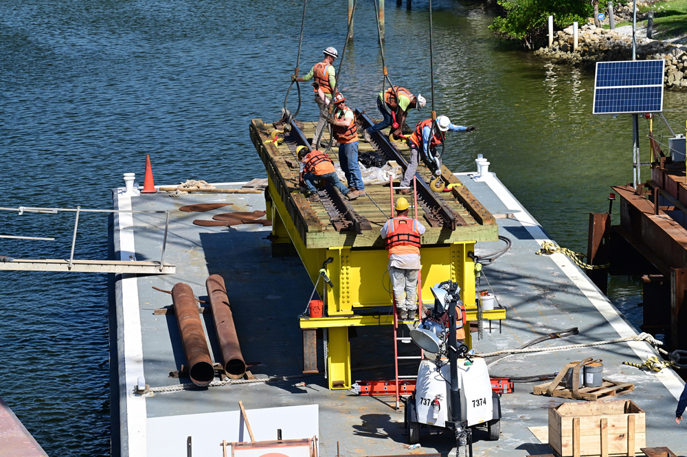 Construction workers with section of bridge on platform