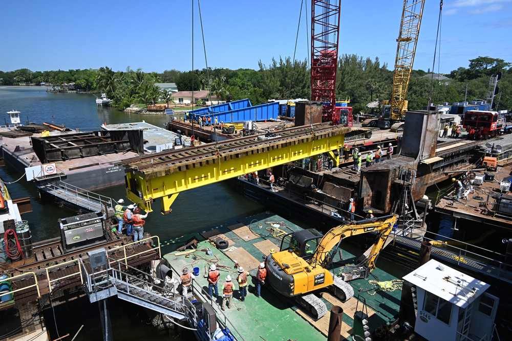 Section of bridge suspended by cranes