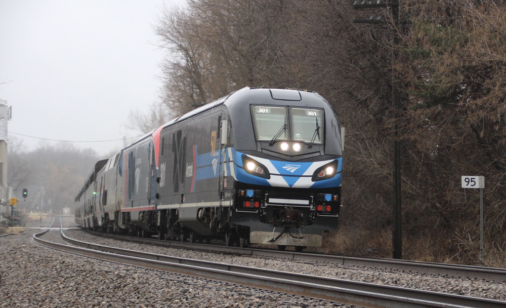 Passenger train led by black locomotive with blue and white stripes