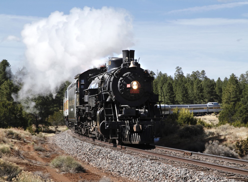 Black steam locomotive pulling passenger train around curve