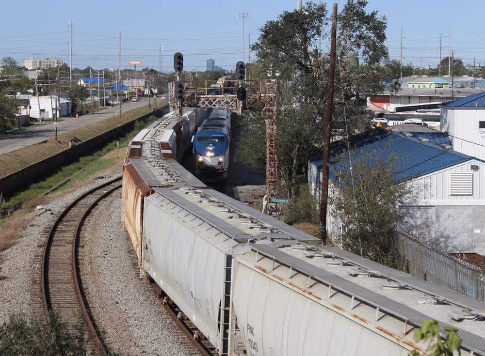 Passenger train approaches curve with freight train on adjacent track