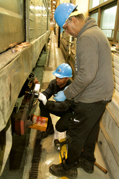 Two men working at side of vintage subway car